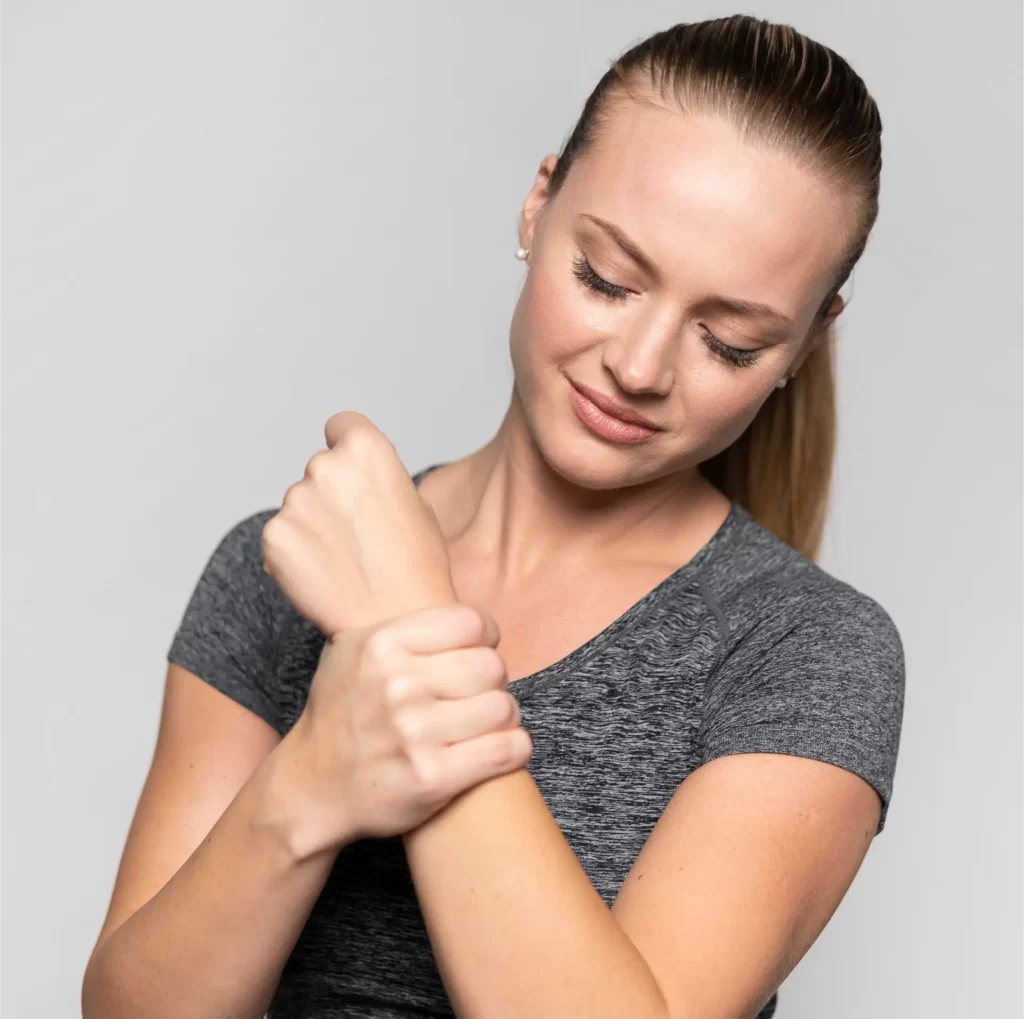 Mulher segurando o pulso, indicando dor e inflamação nas articulações.